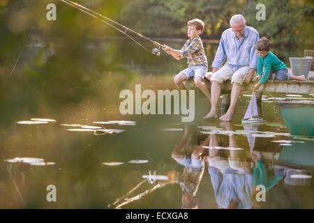 Großvater und Enkel Angeln und spielen mit Spielzeug Segelboot am See Stockfoto