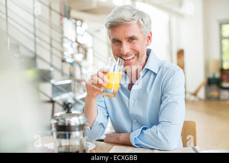 Ältere Menschen trinken Orangensaft am Frühstückstisch Stockfoto