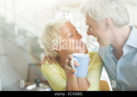 Älteres Ehepaar umarmt mit Kaffeetasse Stockfoto