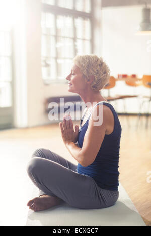 Ältere Frau, die Meditation über Gymnastikmatte Stockfoto