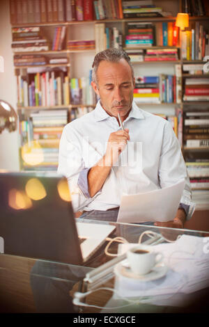 Geschäftsmann lesen Papierkram am Schreibtisch home-office Stockfoto