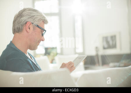 Älterer Mann mit digital-Tablette auf sofa Stockfoto