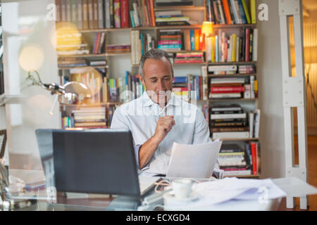 Geschäftsmann lesen Papierkram am Schreibtisch home-office Stockfoto