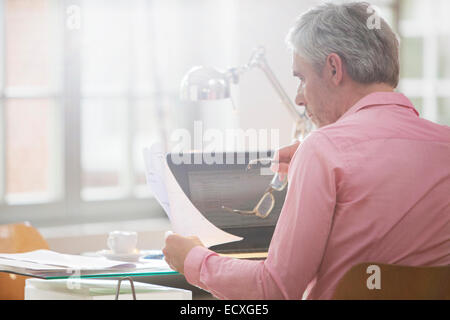 Geschäftsmann lesen Papierkram am Schreibtisch home-office Stockfoto