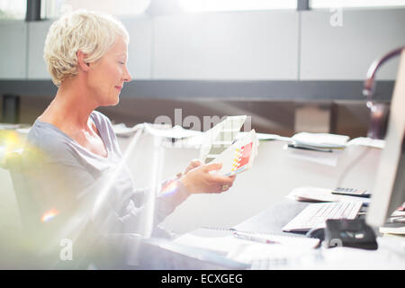 Geschäftsfrau Prüfung Farbkarten am Schreibtisch Stockfoto