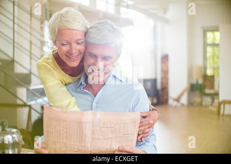 Ältere Frau umarmt Mann lesen Zeitung Stockfoto