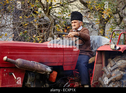 Senior Farmer auf einer alten roten Traktor Pflügen seinen Garten im Hinterhof Stockfoto