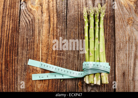 Konzept für gesunde Ernährung mit frischem Spargel und ein Maßband auf einem Holzbrett Stockfoto