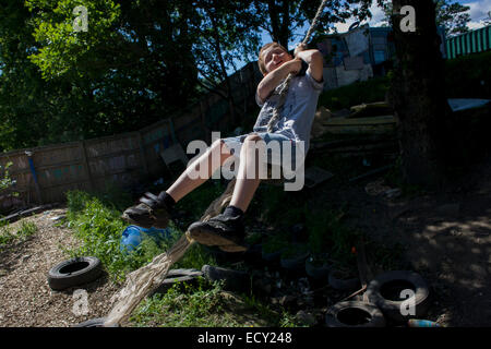 Junge Schaukeln am Seil auf Risiko abgeneigt Spielplatz Plas Madoc Estate, Ruabon, Wrexham Wales das Land fordert. Stockfoto