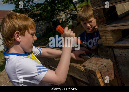 Jungen nutzen Zimmermannshammer in Risiko abgeneigt Spielplatz Plas Madoc Estate, Ruabon, Wrexham Wales das Land fordert. Stockfoto