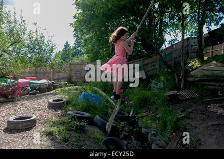 Mädchen schwingt auf Seil Schaukel auf Risiko abgeneigt Spielplatz Plas Madoc Estate, Ruabon, Wrexham, Wales das Land fordert. Stockfoto