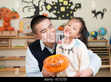 Kindergärtnerin und Mädchen Kürbis schnitzen Stockfoto