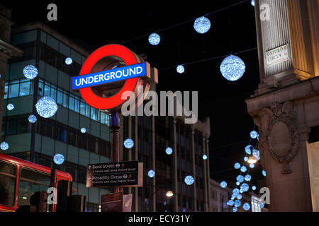 LONDON, UK - Dezember 20: Nachts Schuss von London underground Ortseingangsschild mit Weihnachtsbeleuchtung im Hintergrund. 2 Dezember Stockfoto