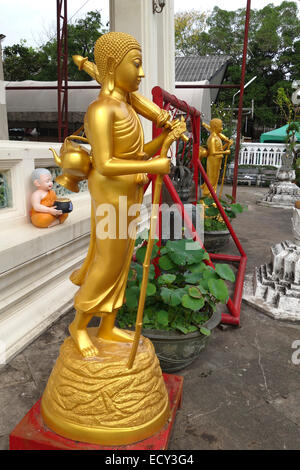 Statue von Wandern Pilger Buddha mit Sonnenschirm und Zuckerrohr vor buddhistischen Tempel Bangkok, Thailand. Stockfoto