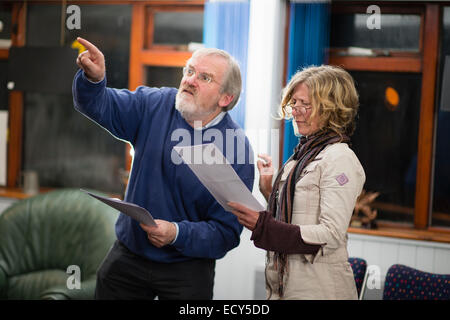 Ein Mann und eine Frau, zwei Laien Laiendarstellern in den Proben für eine Drama-Theater-Performance - Lesung ihre Linien von Skripts, die sie in ihren Händen halten. UK Stockfoto
