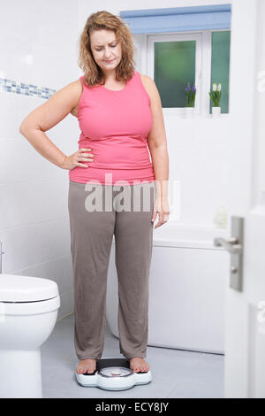 Übergewichtige Frau wiegen sich auf die Waage im Badezimmer Stockfoto