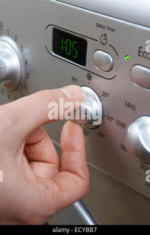 Frau, die kühlere Temperatur auf Waschmaschine Engergy speichern auswählen Stockfoto