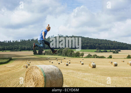 Landwirt über Heuballen im Bereich springen Stockfoto