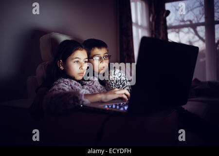 Gemischte Rassen Schwestern mit Laptop in der Nacht Stockfoto