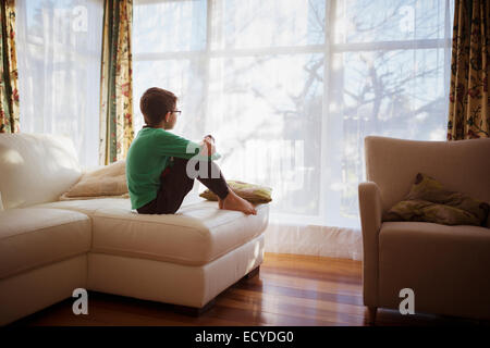 Gemischte Rassen Mädchen suchen Wohnzimmerfenster Stockfoto