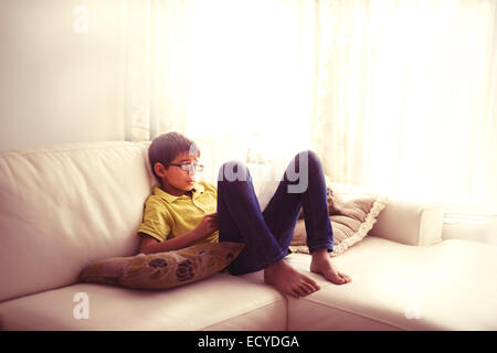 Gemischte Rassen junge Lesebuch auf Sofa im Wohnzimmer Stockfoto