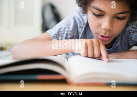 Gemischte Rassen junge Lesebuch am Schreibtisch Stockfoto