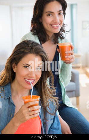 Hispanische Frauen trinken gesunde Karotten-Saft im Wohnzimmer Stockfoto