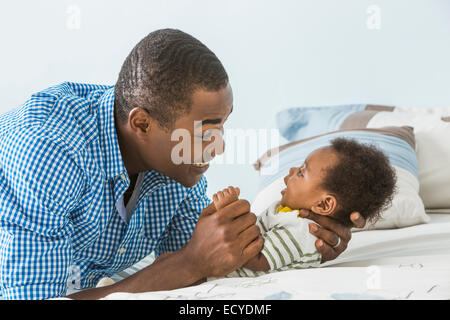 Vater wiegt Baby Sohn auf Bett Stockfoto