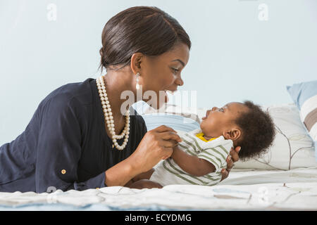 Mutter wiegt Baby Sohn auf Bett Stockfoto