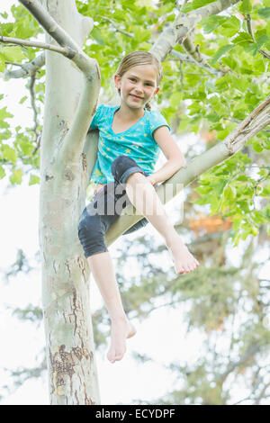Lächelnd kaukasische Mädchen Kletterbaum im freien Stockfoto