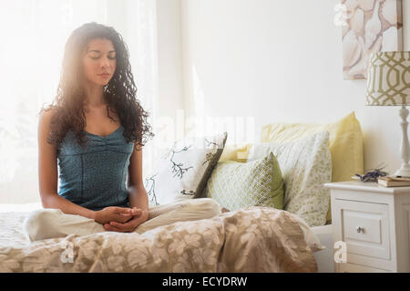 Gemischte Rassen Frau meditieren auf Bett Stockfoto