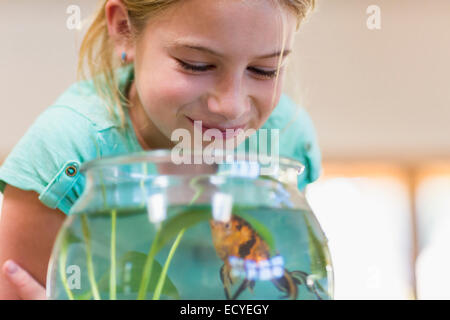 Kaukasische Mädchen bewundern Goldfisch im Goldfischglas Stockfoto