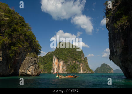 Touristen in einem traditionellen thailändischen Longtail-Fischerboot vor Anker zwischen Kalksteinfelsen, Phang Nga Bay, in der Nähe von Krabi, Thailand Stockfoto