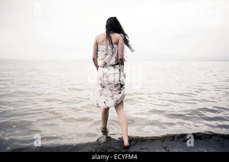 Kaukasische Frau waten im Wasser am Strand Stockfoto