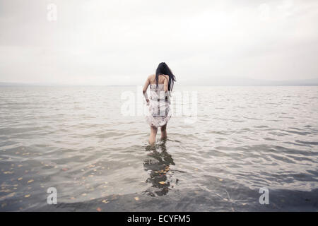 Kaukasische Frau waten im Wasser am Strand Stockfoto