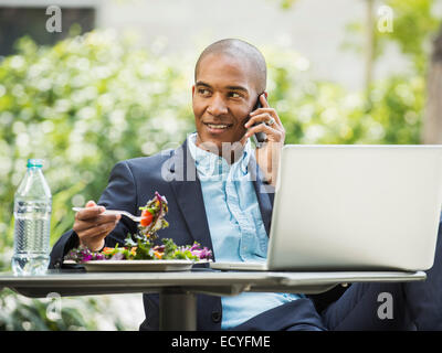Schwarze Geschäftsmann arbeiten und Essen im freien Stockfoto