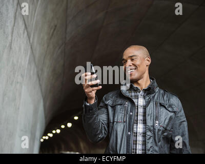 Schwarzer Mann mit Handy im städtischen tunnel Stockfoto