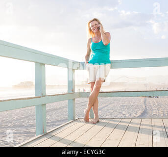 Kaukasische Frau am Handy am Boardwalk am Strand Stockfoto