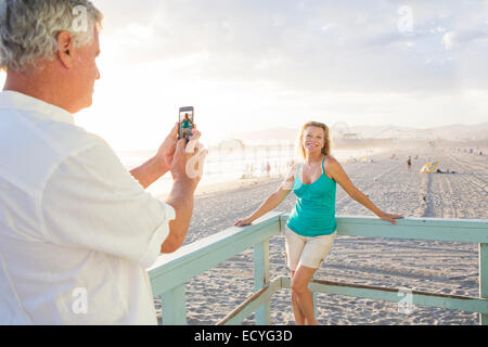 Kaukasischen Mann nehmen Foto von Frau am Boardwalk am Strand Stockfoto