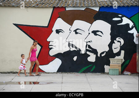 Havanna, Kuba - 16. Mai 2011: Kubanische Frau und Kind laufen Sie vor Plakatwand mit Mella, Cienfuegos und Guevara. Stockfoto