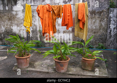 Orangen und Safran Roben buddhistischer Mönche hängen, Wäscheleine im rustikalen Hof mit Topfpflanzen Stockfoto