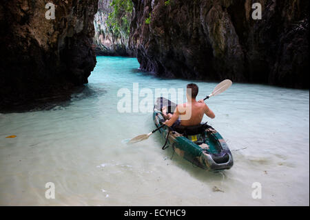 Junger Mann Kajak durch tropischen Flachwasser in Richtung engen Rock Bucht auf Koh Phi Phi, Thailand Stockfoto