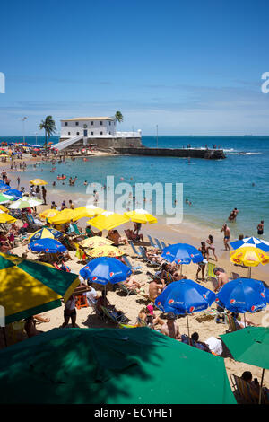 SALVADOR, Brasilien - 13. Oktober 2013: Beachgoers versammeln sich unter bunten Sonnenschirmen am hellen Nachmittag am Porto da Barra. Stockfoto