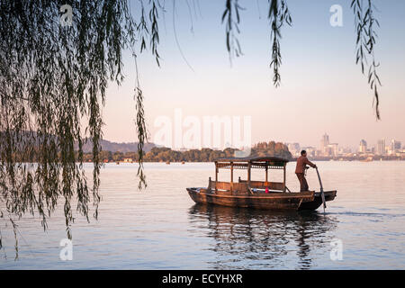 Hangzhou, China - 5. Dezember 2014: Traditionelle chinesische hölzerne Freizeit Boot mit Bootsmann auf dem Westsee schwimmt. Berühmten park Stockfoto