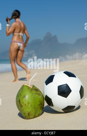 Brasilianische Frau im Bikini geht vorbei an frischem Grün trinken Kokosnuss Coco Gelado Fußball Fußball Ipanema Strand Rio de Janeiro Stockfoto