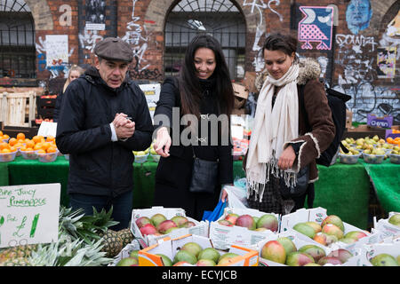 Straßenszene mit einem Gewerbetreibenden Kunden seine Mangos in Brick Lane Market im East End von London, UK verkaufen wollen. Dieser Bereich ist Stockfoto