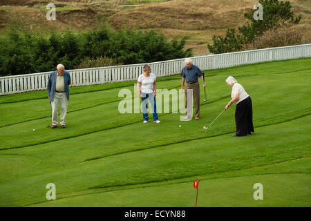 Eine Gruppe von 4 vier Senioren, Rentner, Rentner, auf Urlaub spielen Minigolf, UK Stockfoto