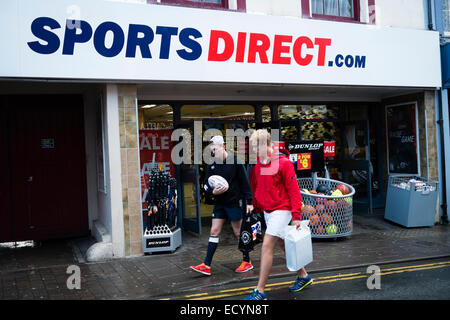 Zwei junge Männer mit ihre Einkäufe zu Fuß aus einem Zweig der SportsDirect.Com Hautpstraße Rabatt Ladengeschäft lagern außen UK Stockfoto