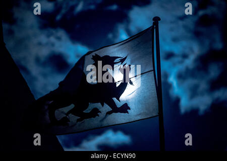 Der Vollmond scheint durch eine walisische Nationalflagge Banner, zeigt das Mondlicht roter Drache-Emblem von Wales in der Silhouette, Wales UK Stockfoto