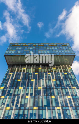 Modernes Bürogebäude mit Glasfassade vor blauem Himmel mit weißen Wolken Stockfoto